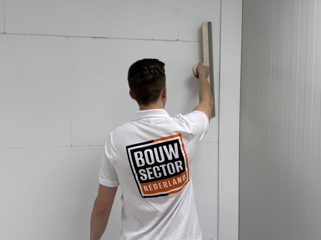 Stukadoor van Bouwsector Nederland zet een rei tegen een wand met zichtbare naden