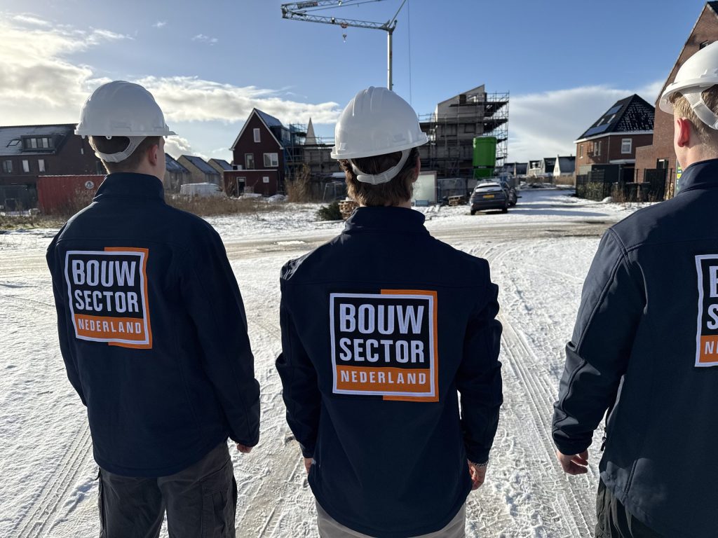 Drie medewerkers van Bouwsector Nederland in werkjas en helm op een bouwplaats